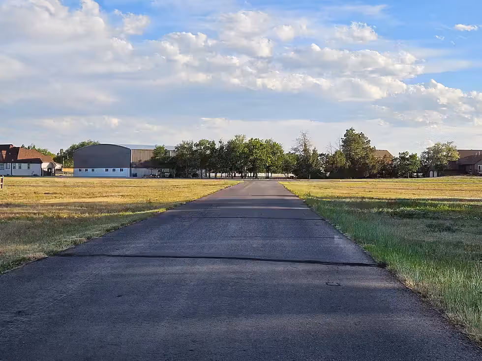 The edge of the Van Aire runway with homes and mature trees beyond.