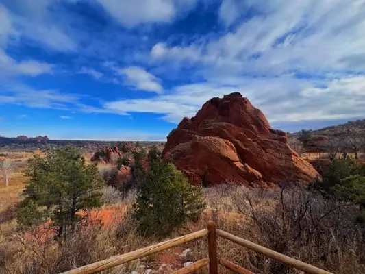 Red rock formations rising from pinon and grass under a winter sky.