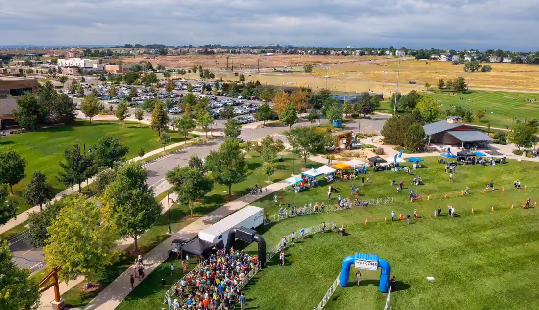 Aerial view of a Front Range town park with playing fields, parking and new subdivisions beyond open ground