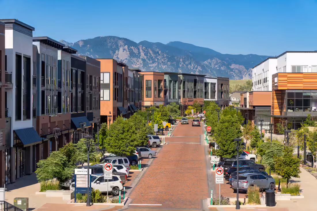 Brick street through Downtown Superior lined with mixed-use blocks, the Flatirons rising behind