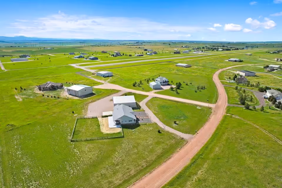 Aerial view of homes, hangars and dirt roads spread across open prairie at Kelly Air Park.