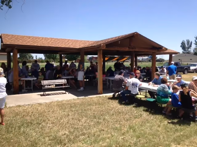 Residents seated at picnic tables under a timber pavilion at Van Aire.