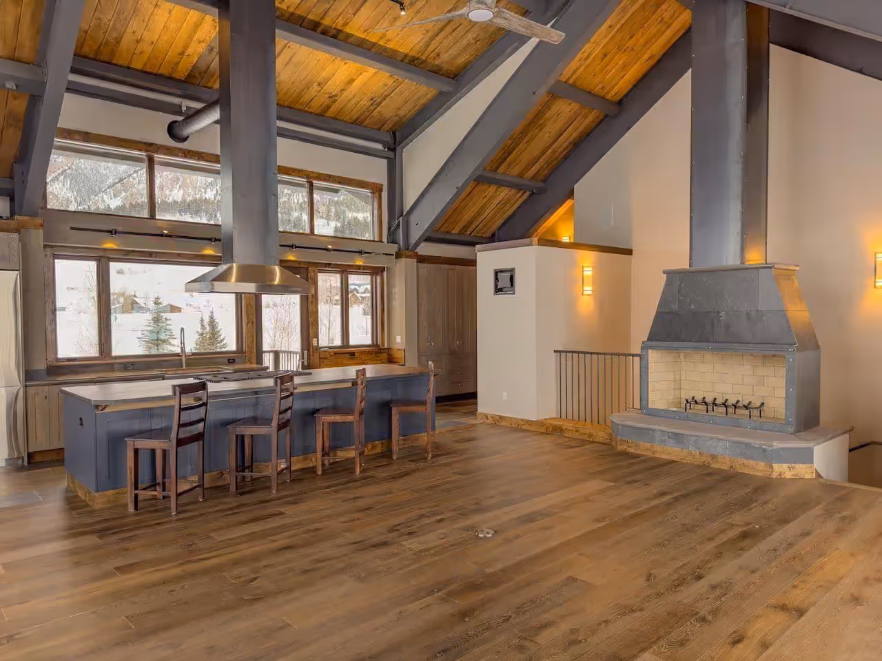 Great room with timber ceilings, stone fireplace and mountain views through tall windows